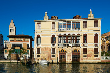 Naklejka premium View of a typical Venetian facade with its façade damaged by the effect of water and a wooden pier for small boats
