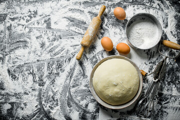Flour background. The dough with a rolling pin, a sieve and a mixer.