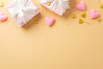 Valentine's Day concept. Top view photo of present boxes with white ribbon bows golden hearts candles and shiny sequins on isolated pastel beige background with empty space