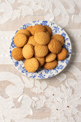 Overhead view of white plate with cookies on table with white tablecloth, vertical, white background, with copy space
