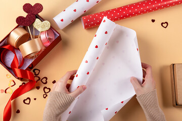 Young woman packing gift for her boyfriend. Close up of female hands packing gift for boyfriend. Preparing for the Valentine's Day.