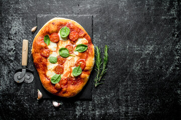 Homemade pizza with sausages, cheese and spinach.