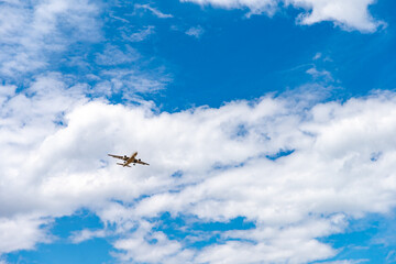landing plane on blue sky with clouds