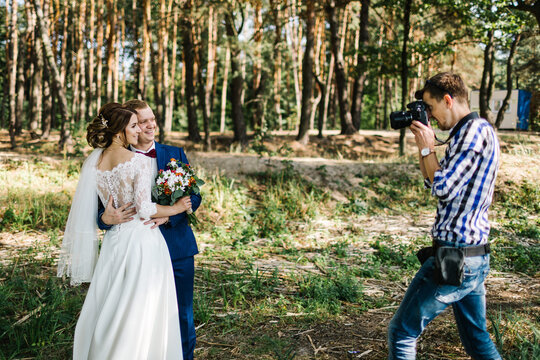 A wedding photographer takes pictures of the bride and groom in nature. Photographer in action.