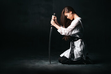 Ninja samurai woman kneeling and sitting on the floor, holding katana sword. The concept of loyalty...