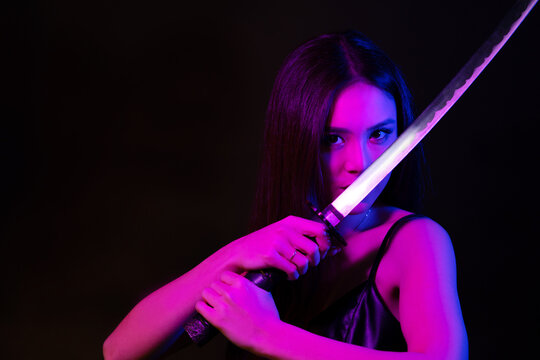 Beautiful asian woman with katana sword in neon lights. Copy space.