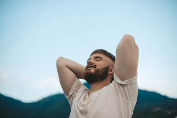 happy handsome man relax nature, young calm carefree man traveler with open raised hands enjoy...