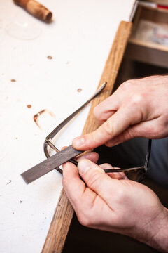 Ein Optiker feilt mit einer Feile am Gestell einer Brille