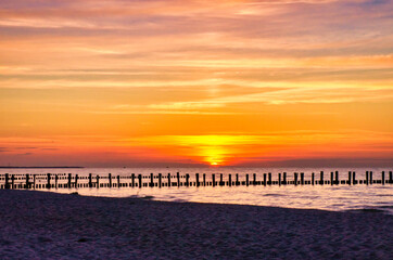 At sunset, the groynes jut into the sea. The sun shines on the Baltic Sea. Landscape
