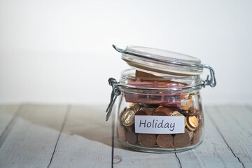 a jar full of coins and banknotes with a label that says holiday