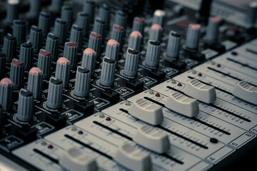 Closeup and detail of audio mixing console with faders and knobs