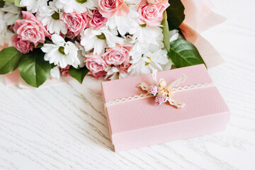 Beautiful bouquet of rose and chrysanthemums flowers and pink gift box on white table background....