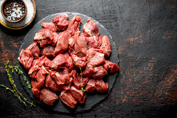 Cut raw beef on a stone Board with thyme and seasonings in bowls.