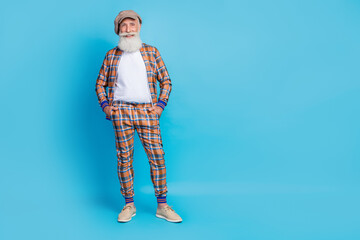 Fototapeta premium Full length photo of cheerful stylish macho dressed fashionable plaid outfit hand pocket empty space isolated on blue color background