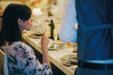 Beautiful stylish woman toasting with wine glass on wedding reception in restaurant. Guests...