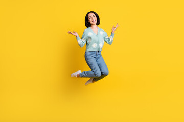 Fototapeta na wymiar Full size photo of satisfied adorable woman bob hairstyle dressed blue pullover flying raise palms up isolated on yellow color background