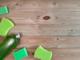 Fototapeta na wymiar Set of cleaning products - template for advertising, article, flyer with copy space. Flatlay. Detergent and sponges for cleaning in green on wooden background. Spring cleaning concept. Space for text