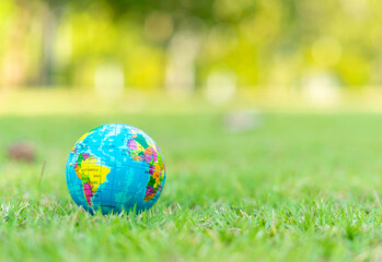 Global in sunlight on green grass at park with copy space. Earth and water and save the world concept.