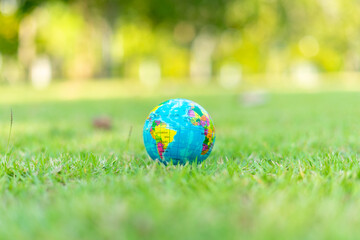 Global in sunlight on green grass at park with copy space. Earth and water and save the world concept.
