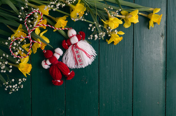 Martenitsa, Martisor, on a green wooden table framed with yellow daffodils