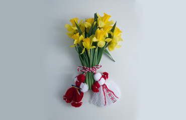 Bouquet of yellow daffodils tied with red-white martenitsa, martisor on white background 