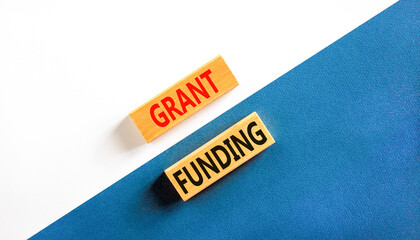 Grant funding symbol. Concept words Grant funding on wooden blocks. Beautiful white and blue background. Business and grant funding concept. Copy space.