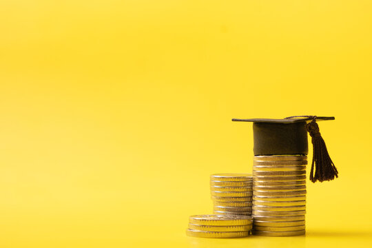Graduated cap with coins on yellow background. Savings for education, financial literacy concept