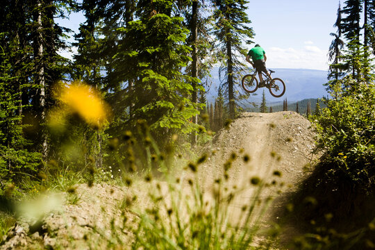 Man jumping mountain bike at a bike park, Vernon, BC