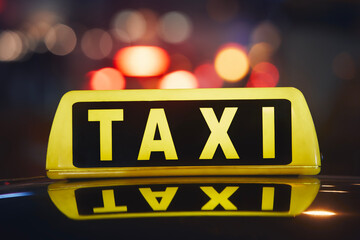 Selective focus on taxi sign on roof of car against busy city street at night. .