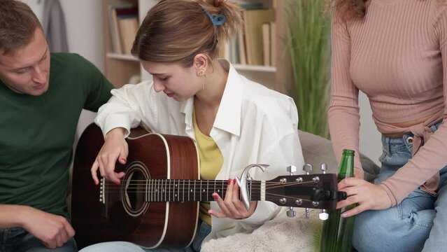 Guitar beginner. Inspired woman. Friendly support. Casual man teaching girlfriend arranging chords in light room interior.
