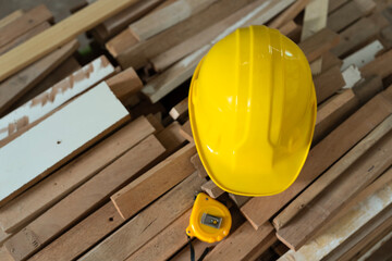 Yellow helmet on a wood plank with tape measure for carpenter tool at a carpentry shop