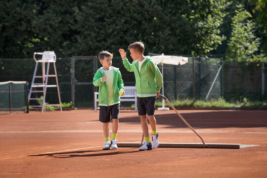 Two young boys preparing tennis court, Bavaria, Germany