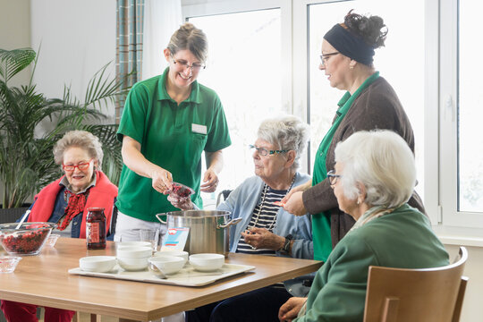 Nurses preparing dessert with senior residents in rest home