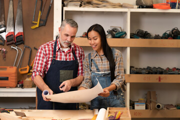 Carpenter lovers looking at model blueprints, discuss wooden material specs for building furniture at carpentry shop, and handmade household furnishing traditionally. Family business, entrepreneur