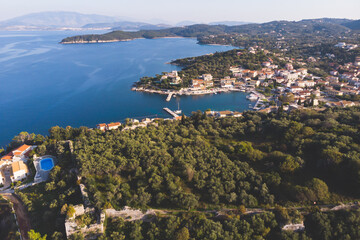 Fototapeta premium Aerial drone view of Kassiopi, village in northeast coast of Corfu island, Ionian Islands, Kerkyra, Greece in a summer sunny day, with marina, town, beach and castle