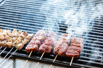 Close-up of skewers of raw meat and chicken on the grill.