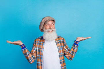 Fototapeta Photo of dreamy thoughtful man pensioner dressed checkered costume comparing arms empty space isolated blue color background obraz