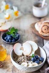 Healthy breakfast, oatmeal or granola with blueberries, apple and honey on a rustic wooden background