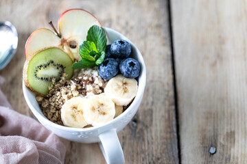 Healthy breakfast, oatmeal or granola with blueberries, apple, kiwi and mint on a rustic wooden background. close-up. Copy space