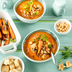 Vegetarian autumn pumpkin and carrot soup with cream, seeds and cilantro micro greens. Comfort food