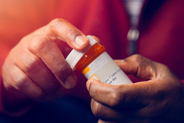 close up of man at home sitting down handling prescription pill bottle