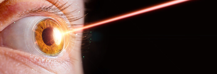 close up of female eye with laser beam hitting the iris