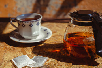 Warm tea with teapot and tea bag on natural wood background