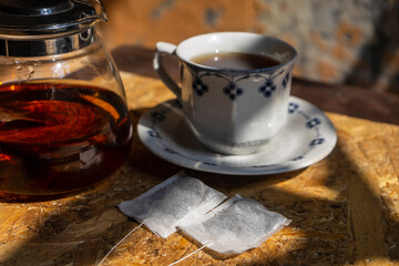 Tea concept background with white tea cup and teapot with fresh tea on wooden table