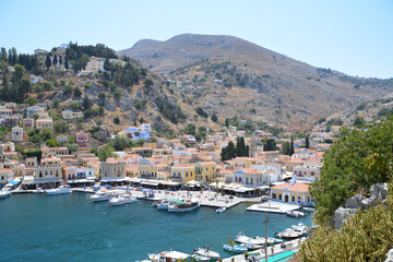 Fototapeta na wymiar bay of water with boats and multicolored greek buildings of Symi island, topview