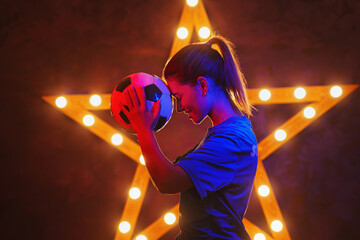  Portrait of young female soccer player with soccer ball standing with a shining star in the back....