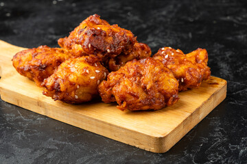 Fried chicken pieces in Asian style spicy sauce close-up. Deep fried chicken fillet.