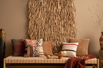Warm composition of living room interior with dried straw on wall, couch, colorful pillows, carlet...