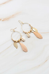 A pair of earrings on a marble background with copy space. Fashion earrings for women.