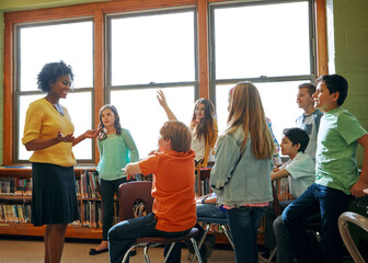 Learning, education and student with questions for teacher in middle school classroom. Library, scholarship group and male learner raising hand to answer question, studying or help with black woman. - obrazy, fototapety, plakaty